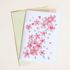 Kort med lyserøde sakura blomster og lysegul kuvert