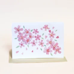 Kort med lyserøde sakura blomster og lysegul kuvert